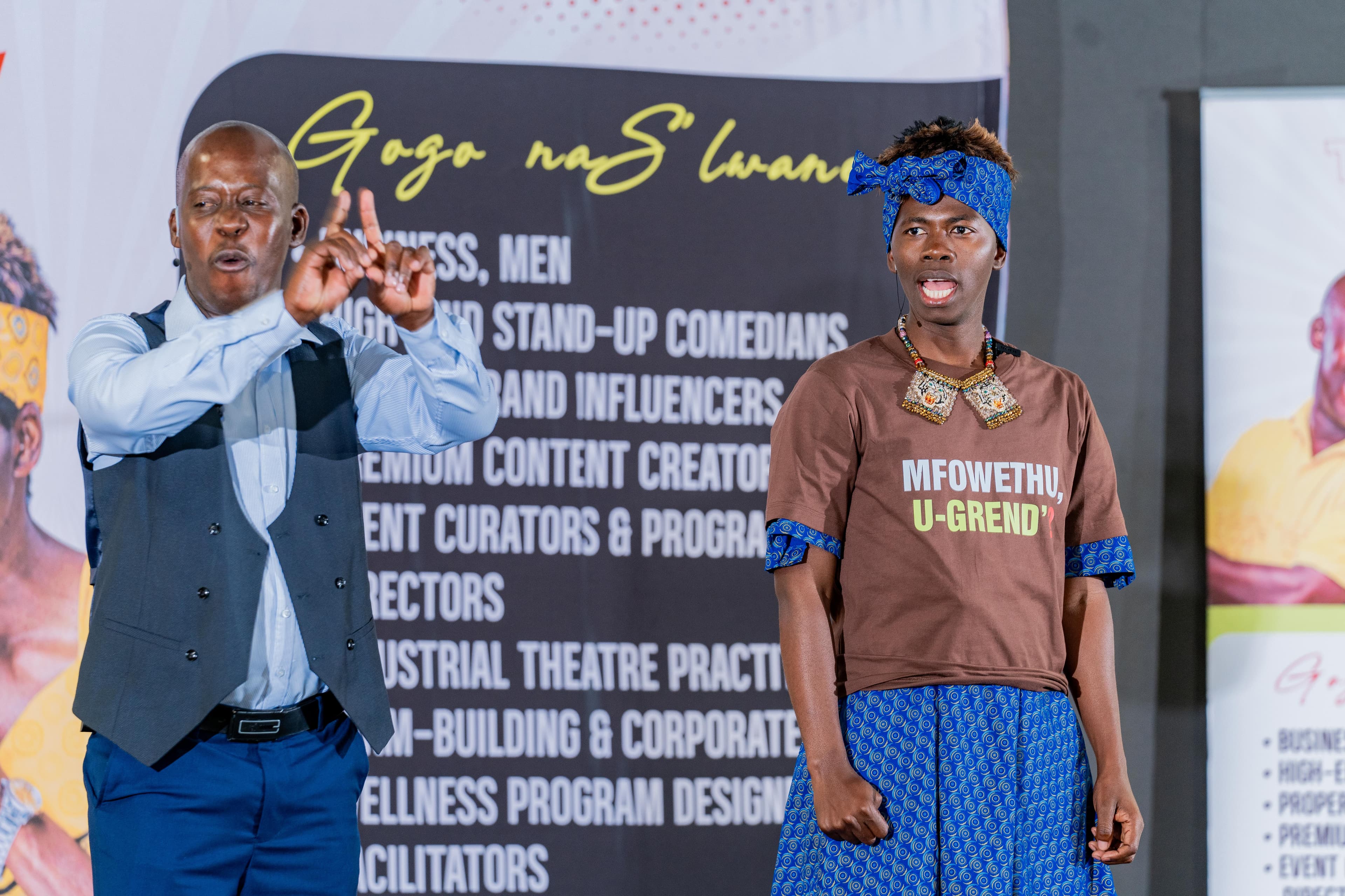 Gogo and Slwane mid-sketch on stage in front of their banner
